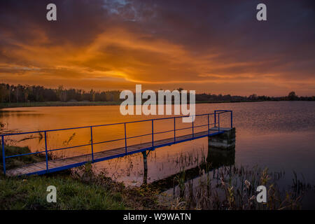Un pont sur l'étang et les nuages en soirée après le coucher du soleil. Staw, Pologne Banque D'Images