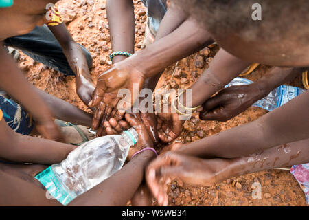 Les enfants africains dans le désert à l'extérieur de Niamey, Niger, se lavant les mains de l'eau recueillie dans une bouteille en plastique. Banque D'Images