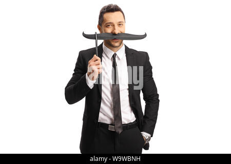 Jeune homme en costume holding fake moustaches sur un bâton isolé sur fond blanc Banque D'Images