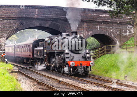 Aucune locomotive 76084 class 4MT, il roule sous le pont à Weybourne gare avec un râteau de calèches Banque D'Images