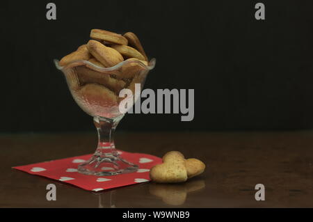Un verre tasse pleine de cookies en forme de cœur, sur une serviette rouge coeurs blancs où sont dessinés. Copy space Banque D'Images