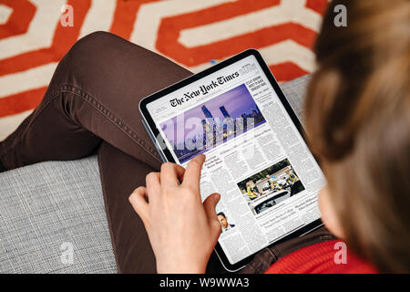 Paris, France - Mar 15, 2019 : Woman reading on iPad tablette numérique Pro les dernières journal The New York Times couvrir avec breaking news à propos du quartier des affaires de Manhattan Banque D'Images