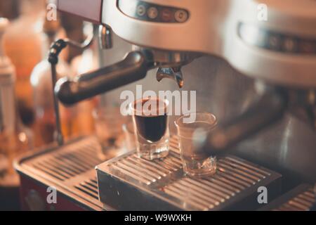 Gros plan de tasses à café sur un égouttoir à machine espresso plateau Banque D'Images