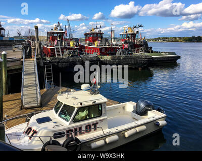 Portsmouth, New Hampshire / USA - 17 octobre 2018 : trois remorqueurs rouge et un bateau-pilote sont amarrés dans le port de Portsmouth sur une journée ensoleillée d'automne. Banque D'Images