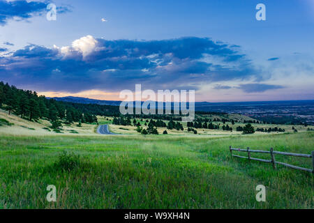 Route de montagne menant à l'flatirons à Boulder, Colorado, avec clôture et nuages en arrière-plan Banque D'Images