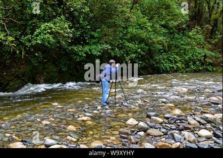 Un photographe est debout au milieu d'une rivière avec son appareil photo sur un trépied de la prise d'une photo Banque D'Images