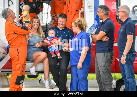 Jennie et riche Powell avec leurs jumeaux Jenson, gauche, Ruben, droite, qui célèbrent leur premier anniversaire en rencontrant les équipes de garde-côtes HM pour la première fois depuis que Jennie a été évacué par eux dans un hélicoptère à Oxford de Cornouailles après qu'elle entre en travail à 22 semaines avec ses jumeaux, l'accouchement le plus jeune avant terme survivant des jumeaux nés en Grande-Bretagne. Sur la photo (de gauche à droite) Le chef d'équipage Ian Copley, Jenson, Jennie, Ruben, riche, sage-femme Jane Parke qui accompagnait Jennie sur le vol, Winchman-Paramedic Niall Hanson et Co-Pilot Ivan Hamilton. Banque D'Images