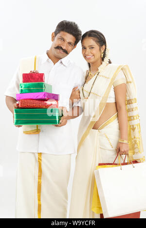 South Indian couple holding gift boxes with shopping bags Stock Photo