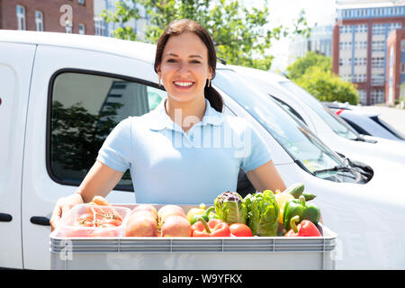 Happy Woman Holding Grocery Shopping Basket with vegetables Banque D'Images