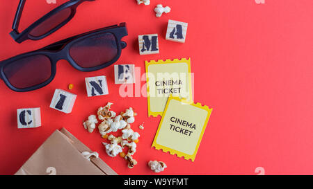 Sac d'artisanat avec popcorn cinéma 3D avec des cubes en bois billets lunettes sur fond rouge Texte flatlay créative Banque D'Images