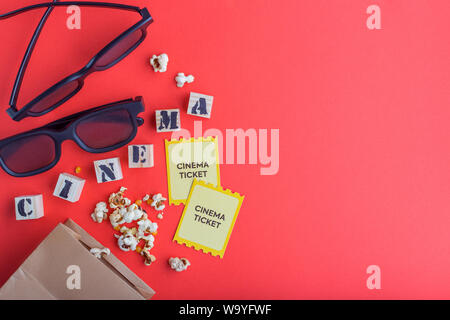 Sac d'artisanat avec popcorn cinéma 3D avec des cubes en bois billets lunettes sur fond rouge Texte flatlay créative Banque D'Images