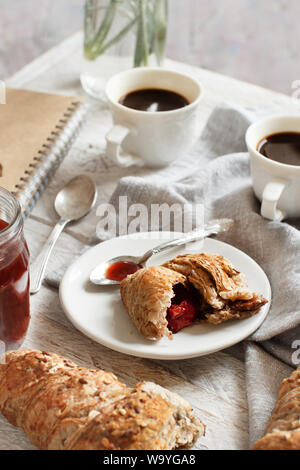 Petit-déjeuner avec du café et un croissant avec confiture de fraise close up Banque D'Images