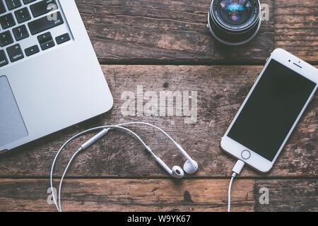 Gros plan d'un ordinateur portable avec un smartphone et un casque sur un arrière-plan en bois et sur un objectif Banque D'Images