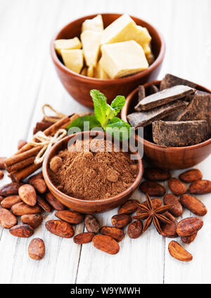 Les fèves de cacao, chocolat, poudre et beurre sur une table en bois blanc Banque D'Images