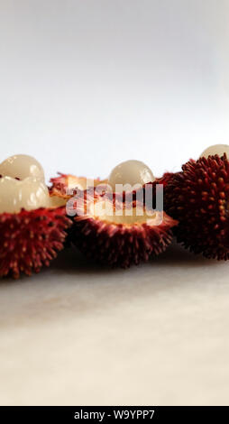 Pulasan pelées fruits en photo verticale. Nom scientifique Nephelium ramboutan-pulasan akea, est un fruit tropical rouge qui est étroitement lié à des ramboutans. Banque D'Images