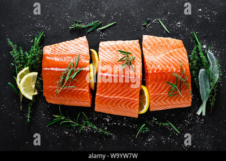 Le saumon. Saumon cru frais Filet de poisson avec des ingrédients, herbes et citron sur fond noir, vue du dessus Banque D'Images