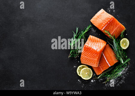 Le saumon. Saumon cru frais Filet de poisson avec des ingrédients, herbes et citron sur fond noir, vue du dessus Banque D'Images