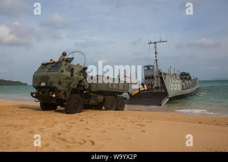 Un utilitaire de débarquement, affecté à la station de transport amphibie USS Green Bay (LPD 20), abaisse la rampe de déchargement d'une grande mobilité du système d'artillerie de la 3e Bataillon, 12e Régiment de Marines, 3e Division de marines, dans le cadre de la simulation d'un raid amphibie, à Kin Bleu, Okinawa, Japon, 14 août 2019. Ce raid amphibie simulée est la première fois que HIMARS ont été insérés par les engins de débarquement, l'utilité, ce qui démontre le Groupe de travail air-sol marin sa capacité de mener des manœuvres interarmes de transport amphibie. (U.S. Marine Corps photo par Lance Cpl. Joshua Sechser) Banque D'Images