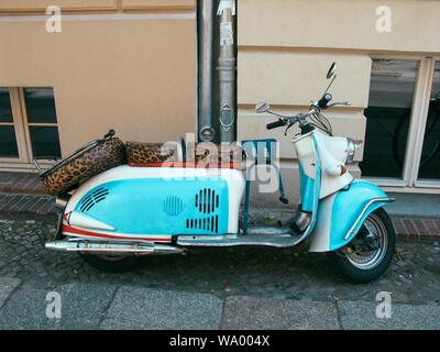 Photo d'une moto bleue et blanche avec des sièges à imprimé tigre garé près d'un bâtiment Banque D'Images