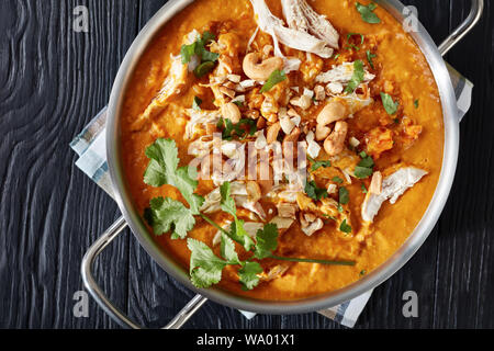 Crémeux de lentilles rouges, les carottes, les pommes et le lait de coco la soupe avec de la viande de poulet dans une casserole en métal sur une table en bois noir, vue de dessus, flatlay, clo Banque D'Images