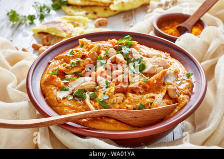 Soupe Mulligatawny avec la viande de poulet et le lait de coco saupoudré de cajou frits dans un bol avec chapati sur une table en bois blanc, Indien et anglais cu Banque D'Images