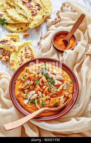 Soupe Mulligatawny épicé chaleureux avec la viande de poulet et le lait de coco saupoudré de cajou frits dans un bol avec chapati sur une table en bois blanc, un Indien Banque D'Images
