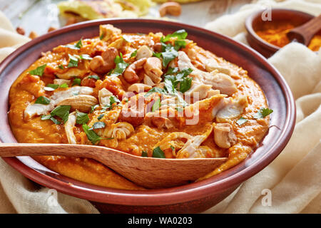 Soupe Mulligatawny avec la viande de poulet et le lait de coco saupoudré de cajou frits dans un bol avec chapati sur une table en bois blanc, Indien et anglais cu Banque D'Images