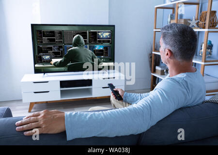 Vue arrière de l'homme regardant la télévision à la maison Banque D'Images