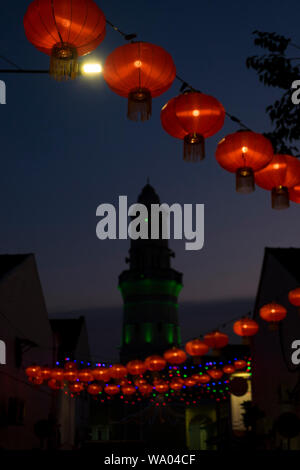 Lanterne chinoise rouge suspendus décoratifs volets traverser la rue à George Town, Penang, Malaisie. Le minaret de la mosquée malais est dans le backgroun Banque D'Images