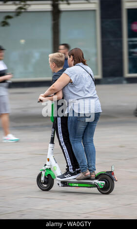 L'E-scooter, scooter électrique, scooter de location, la conduite, à l'Alexander Platz, à Berlin, les gens de remorquage sur un scooter, Banque D'Images