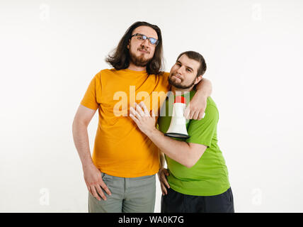 Les jeunes hommes portée au drapeau LGBT couleurs sur fond blanc. Modèles homme de race blanche dans des chemises. L'air heureux, souriant et serrant. La fierté LGBT, des droits de l'homme et choix concept. Maintenant porte-parole. Banque D'Images