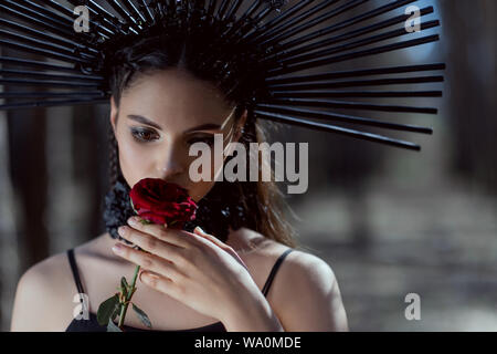 Portrait de jeune femme en costume avec couronne sur la tête rose rouge près de visage Banque D'Images