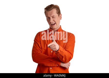 Close-up portrait d'un jeune beau peson de gingembre dans une élégante chemise orange gesticulent et regardant la caméra tout en se posant isolé sur whit Banque D'Images