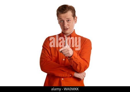 Close-up portrait d'un jeune beau mâle de gingembre dans une élégante chemise orange gesticulent et regardant la caméra tout en se posant isolated on white Banque D'Images