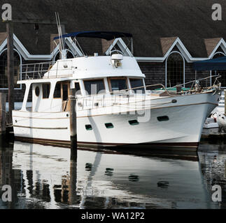 Un grand bateau blanc se reflétant dans l'eau, est soutenue et et accosté à un quai à Bay Shore Long Island. Banque D'Images