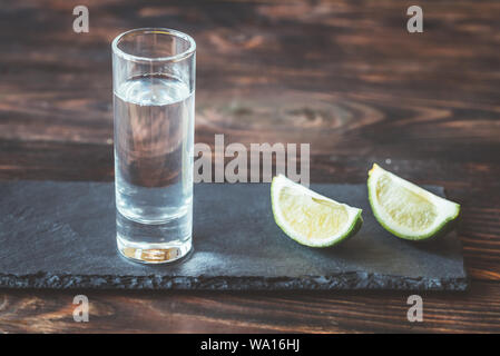 Verre de tequila avec tranches de lime sur le bord en pierre Banque D'Images