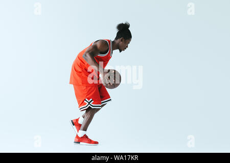 Athletic african american sportsman jouant au basket-ball sur fond gris Banque D'Images