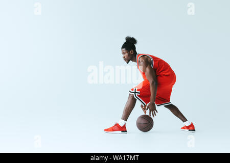 Athletic african american sportsman jouant au basket-ball sur fond gris Banque D'Images