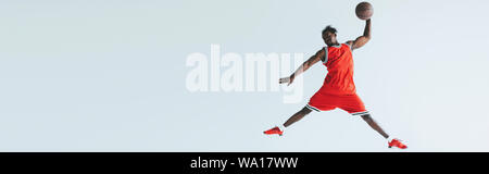 Vue panoramique de tir sportif afro-américain tout en jouant au basket-ball saut isolé sur gray Banque D'Images