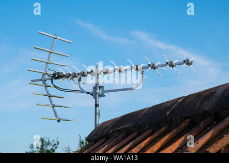 Une antenne TV numérique sur le toit d'une maison contre un ciel bleu Banque D'Images