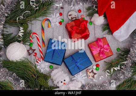 Noël et Nouvel An cadeaux pour la famille sur un fond gris avec des jouets de Noël, branches de conifères, Santa hat, des bonbons, des flocons, des bougies Banque D'Images