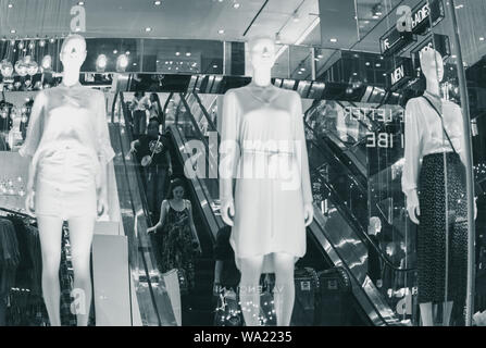Shopping mall interior avec les gens sur l'escalator avec mannequins femmes et plusieurs néons et réflexions au centre Vincom - Ho Chi Minh, Vietnam Banque D'Images