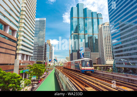 Bangkok - 9 juin 2019 : un BTS train voyage entre les gratte-ciel du centre-ville contre le ciel bleu. Banque D'Images