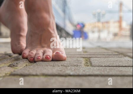 Barefoot girl est debout sur le quai de la gare à côté de la gare Banque D'Images