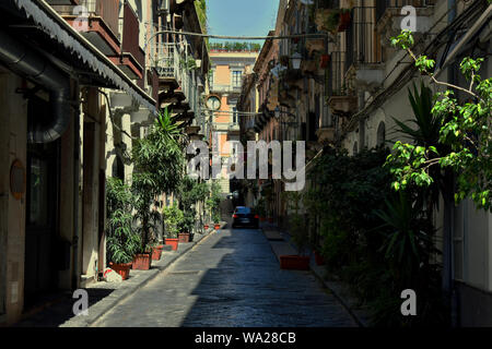 Rue typiquement italien à Catane. Route pavée étroite avec peu d'arbres et bâtiments colorés avec de petits balcons sur les deux côtés Banque D'Images