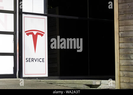 Service Tesla affiche à l'extérieur d'un centre de service de nuit. Banque D'Images