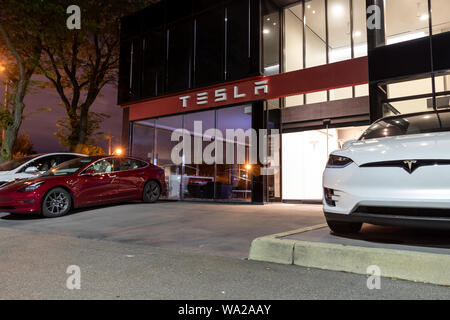 Entrée du concessionnaire Tesla avec de nouveaux véhicules stationnés à l'avant, tard dans la nuit. Banque D'Images