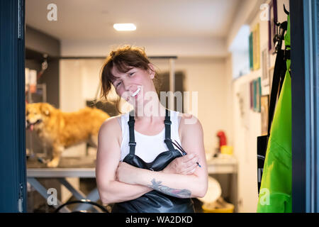 Portrait d'animal professionnel coiffure Femme hippie avec des tatouages tout en se tenant à la porte de son salon de beauté pour les animaux Banque D'Images