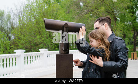 Élégant à la mode pour une promenade en famille. Père et fille sur le pont d'observation. Père aide l'enfant à payer pour l'affichage dans des jumelles. Tim Banque D'Images