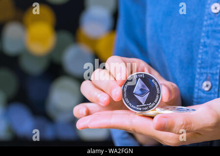 Pièces cryptocurrency - Ethereum. Les femmes occupent la pièce cryptocurrency en main Banque D'Images